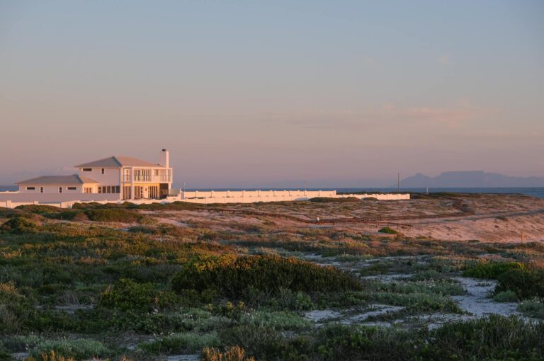 Beautiful coastal house in Yzerfontein, South Africa, at sunset with a tranquil seaside view.