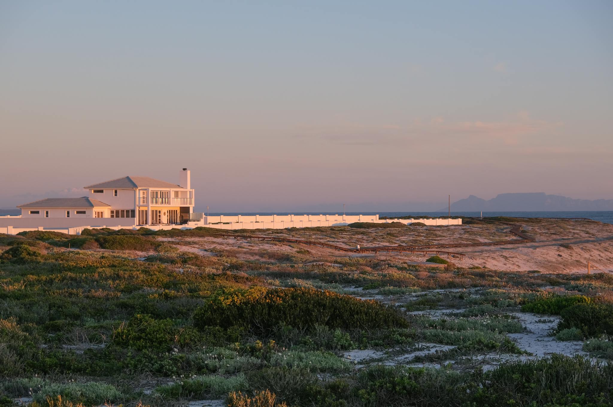 Beautiful coastal house in Yzerfontein, South Africa, at sunset with a tranquil seaside view.